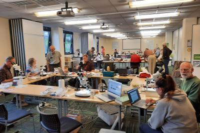 Photo of people in a laboratory with microscopes, computers and books